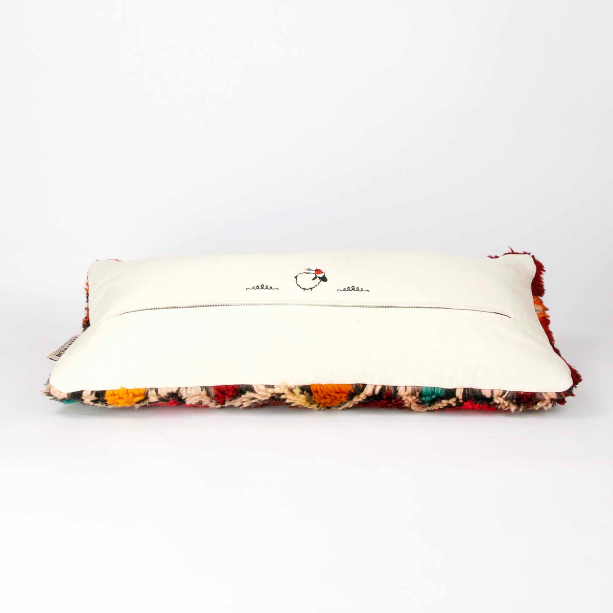 Vintage Berber pillow in red. The cushion is laying on a white ground.