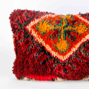 Vintage Berber pillow in red. The left part of the cushion is shown. 