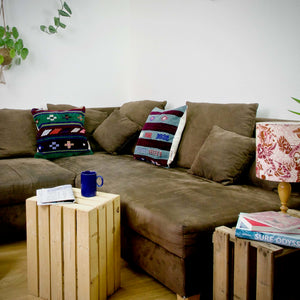 Two Moroccan square throw pillows on a brown couch. 