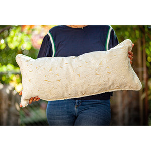 Woman holding a Fluffikon velvet lumbar pillow made from beige moroccan fabric.