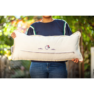 Woman holding a Fluffikon velvet lumbar pillow made from beige moroccan fabric. The pillow back is shown
