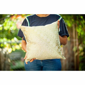 Fluffikon silk square pillow made from golden moroccan fabric. A Woman is holding the golden throw pillow.