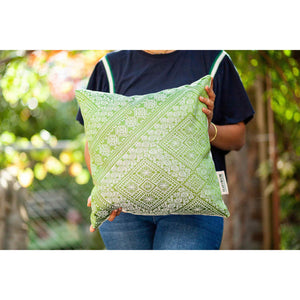 Fluffikon silk square pillow made from green moroccan fabric. The pillow is held by a woman. Size 45x45 cm.