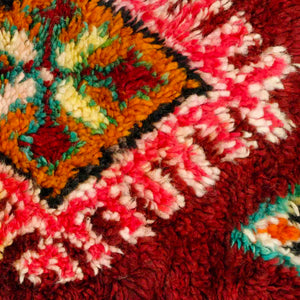 Zoom on the wool of a red Berber pillow made from a vintage wool rug.