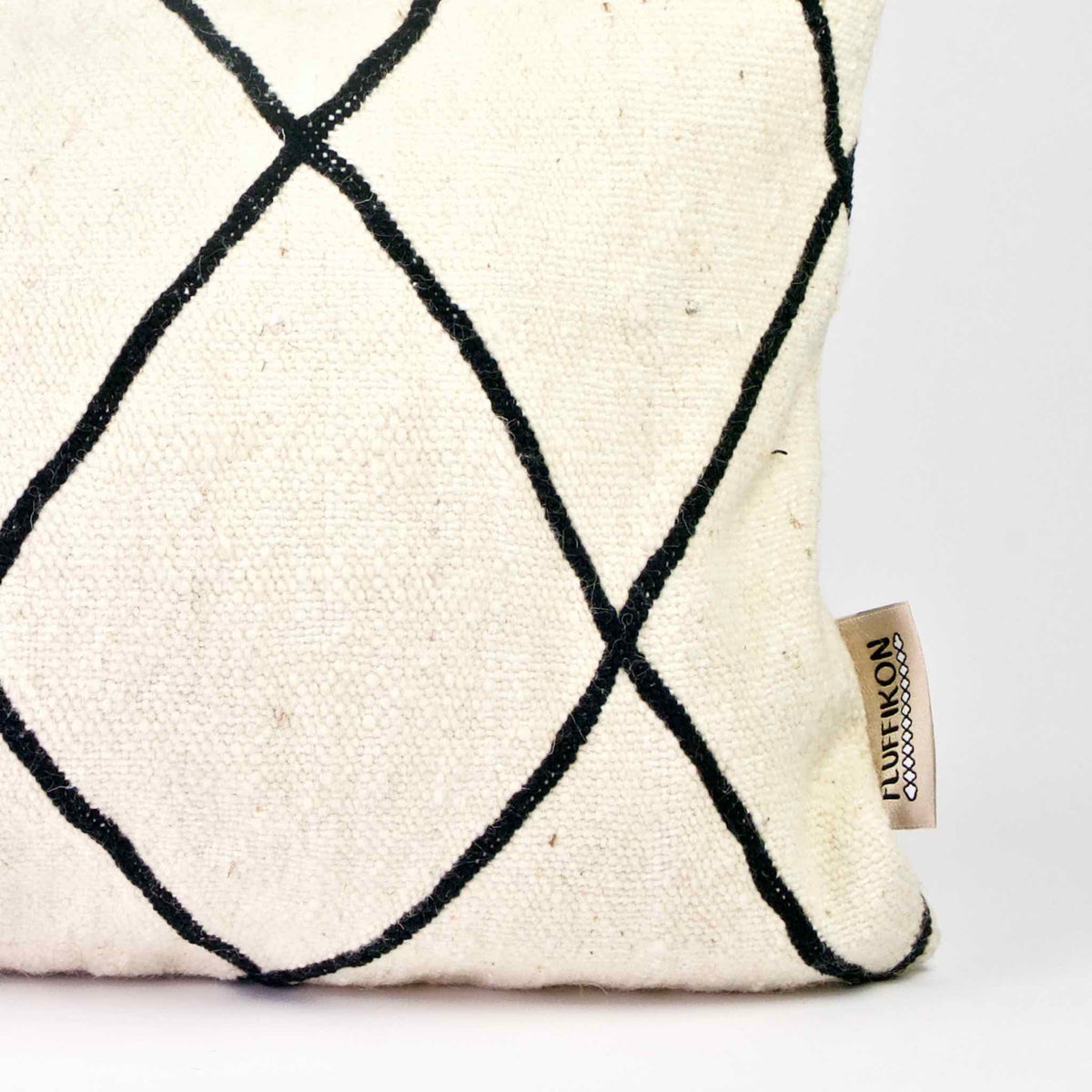 Zoom the corner of a black and white Fluffikon Kilim throw pillow.