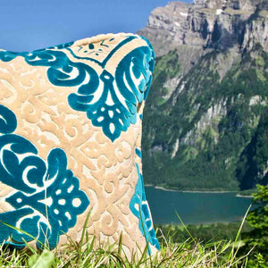 Zoom auf türkises grosses Zierkissen vor Schweizer Bergen.