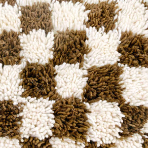 Zoom on a brown checkered Fluffikon throw pillow. The Moroccan pillow  was made from a Berber Beni Ourain wool rug.