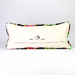 The back of a black Fluffikon Boucherouite lumbar pillow. The Moroccan pillow is made from upcycled clothes. It has colorful patterns in yellow, red, blue and green.