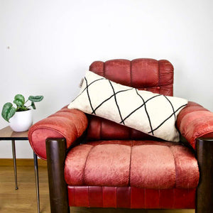 Fluffikon Kilim pillow on a red leather chair.