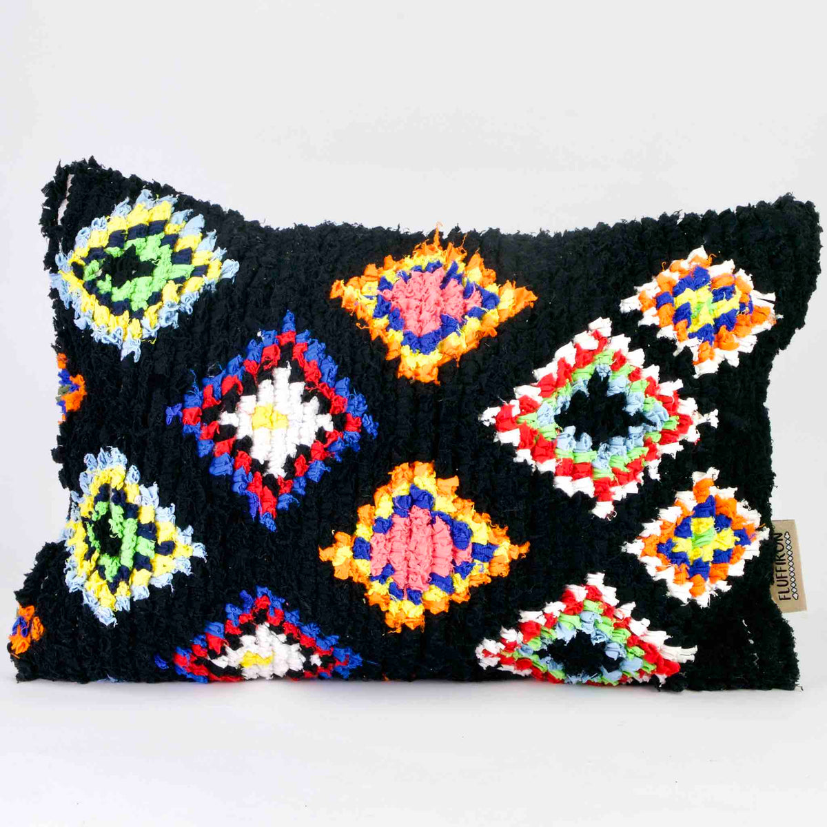 A black Fluffikon Boucherouite throw pillow. The upcycled pillow has colorful patterns embedded in the black fabric.