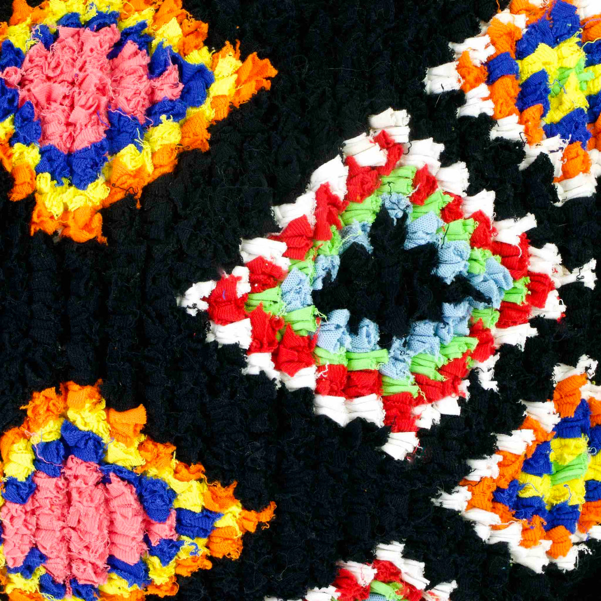 Zoom on a black Fluffikon Boucherouite throw pillow. The upcycled pillow has colorful patterns embedded in the black fabric.