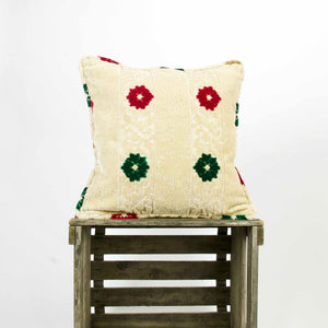 Velvet square pillow on a wooden box. The pillow has red and green flowers on a typical moroccan beige canvas.