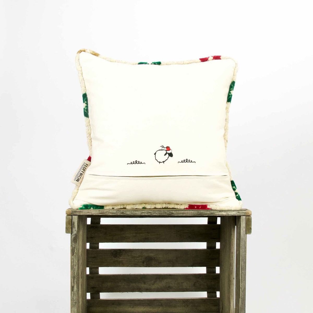 The back of a velvet square pillow on a wooden box.