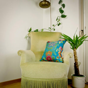 Blue Brocade throw pillow on green chair in stylish living room.