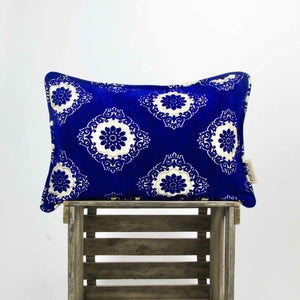 Sapphire blue velvet pillow standing on a wooden box. The pillow has a traditional moroccan look.