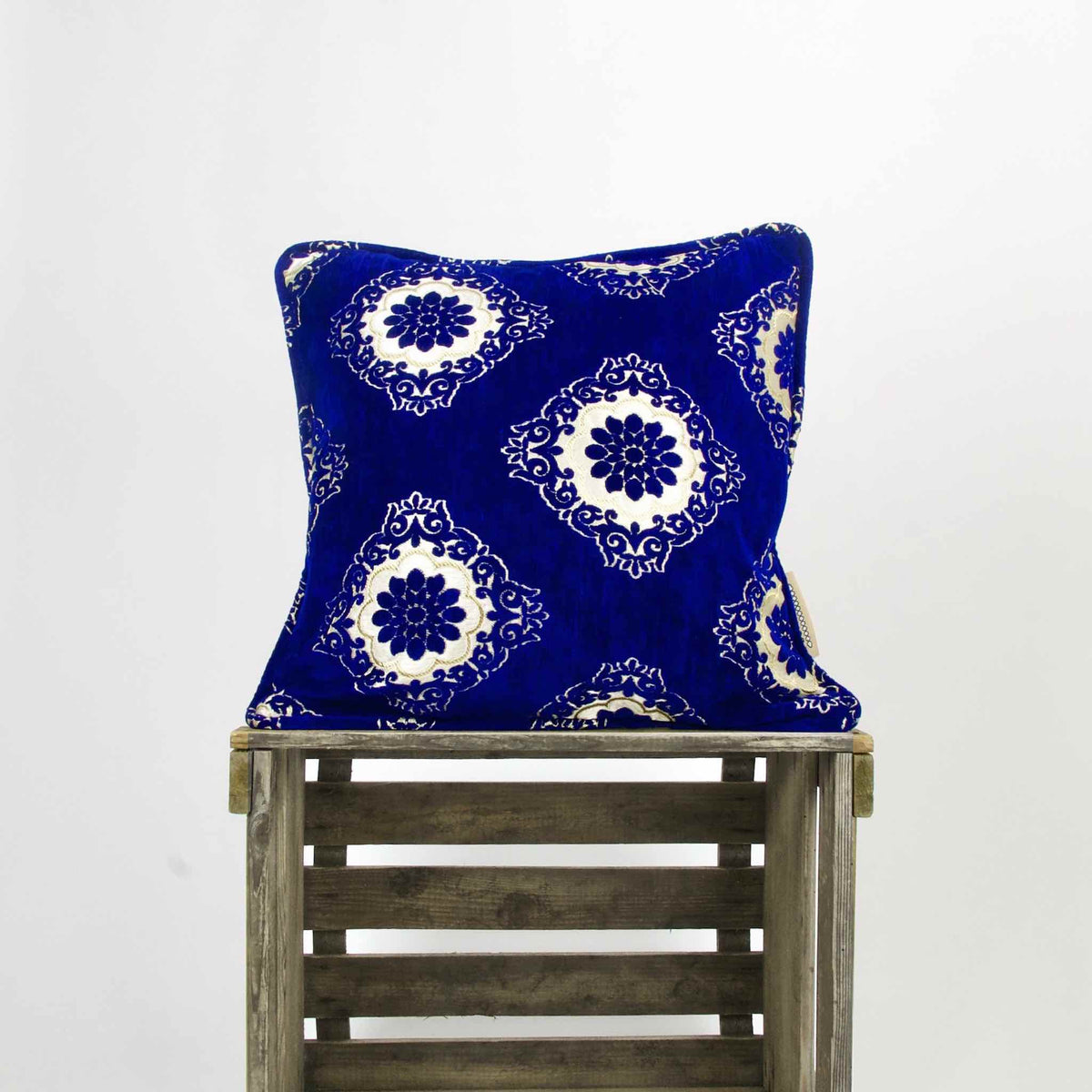 Sapphire blue velvet throw pillow. The blue Fluffikon pillows is standing on a wooden box.
