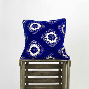 Sapphire blue velvet throw pillow. The blue Fluffikon pillows is standing on a wooden box.