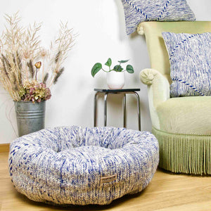 Blue and white Kilim Fluffikon dog bed in front of a living room chair.
