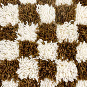 Detailed zoom of the wool texture of a brown checkered Moroccan Berber pillow in front of a white background.