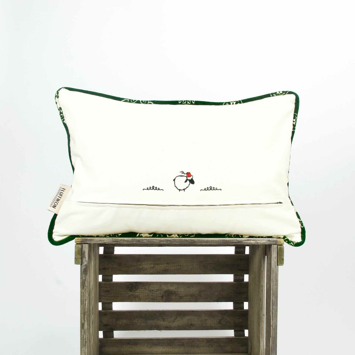 Emerald green velvet pillow with piped edges on a wooden box