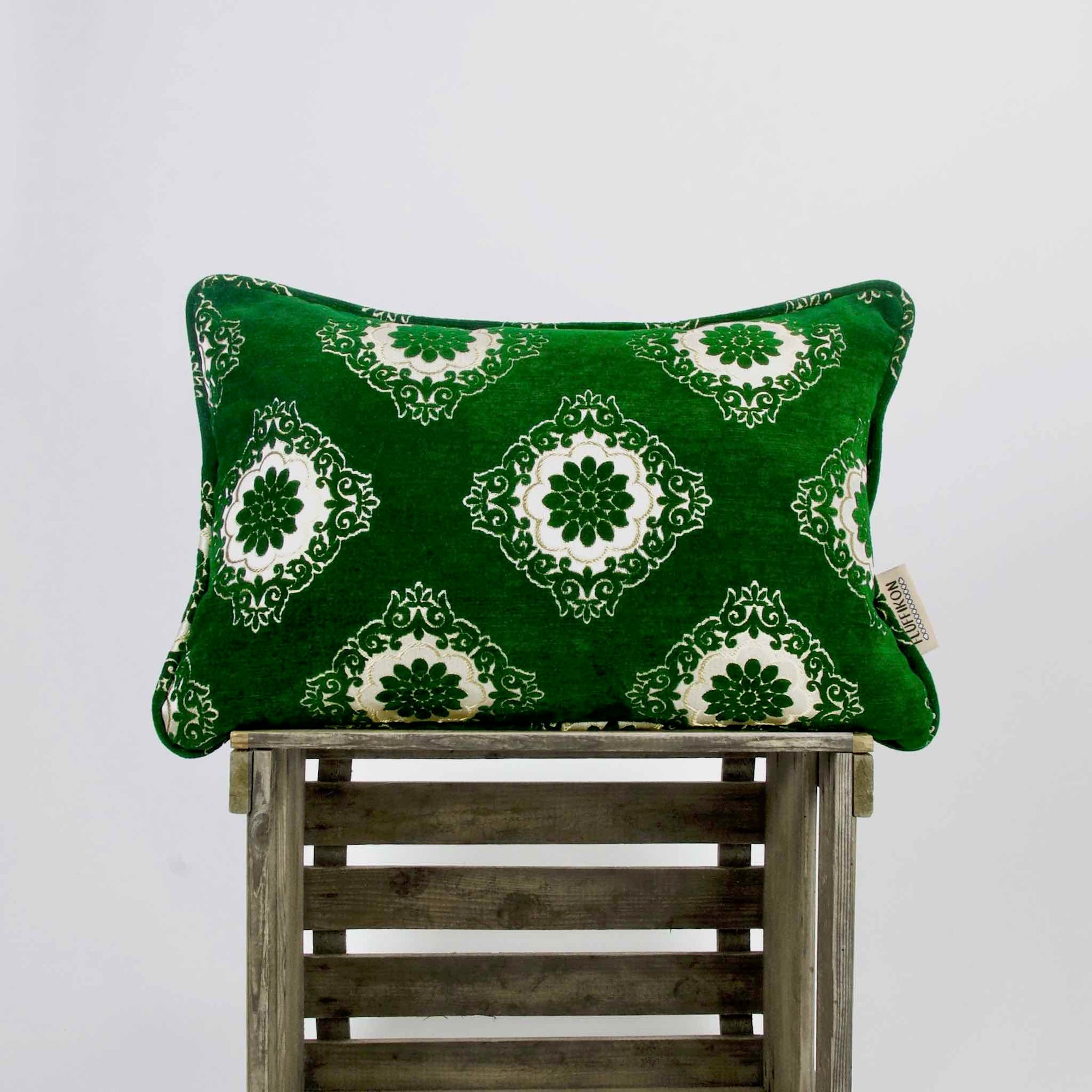 Emerald green velvet pillow on a wooden box.