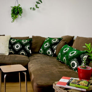 Three emerald green velvet pillows on a brown couch. Lumbar, rectangular and square pillows.