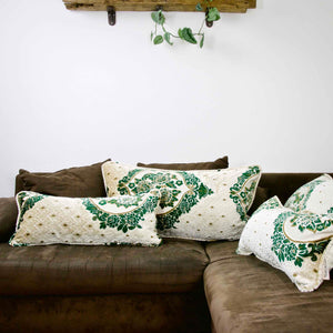 Four large pillows with moroccan patterns on a brown sofa.