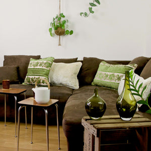 Green and beige velvet pillows on a brown couch.