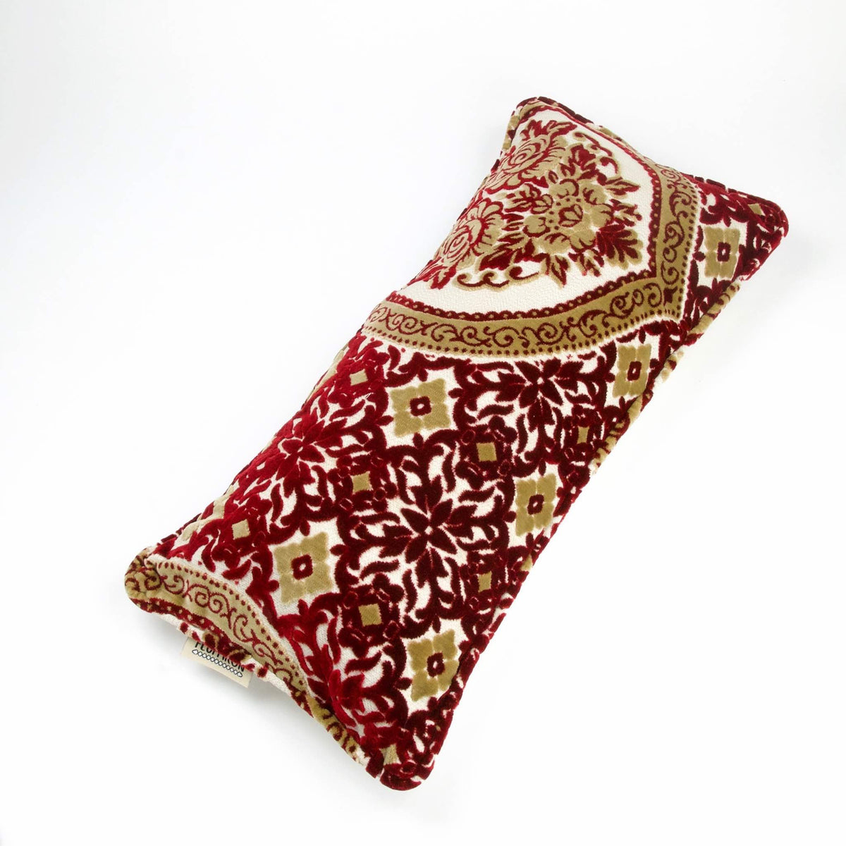 Marokkanisches Sofakissen aus rotem und gelbem Samt vor weißen Hintergrund.