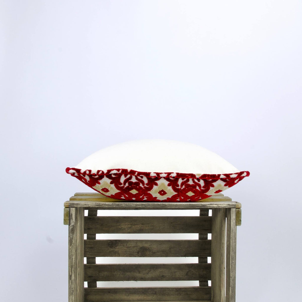 Sie view of aMoroccan couch cushion lying on a wooden box.