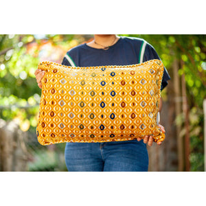 Fluffikon velvet rectangular pillow made from mustard colour fabric with touches of navy blue, grey, cinnamon, and pine green. The pillow is held by a woman.