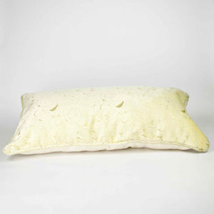 Fluffikon oversized lumbar pillow made from beige velvet with golden threads. The pillow is lying on the ground.