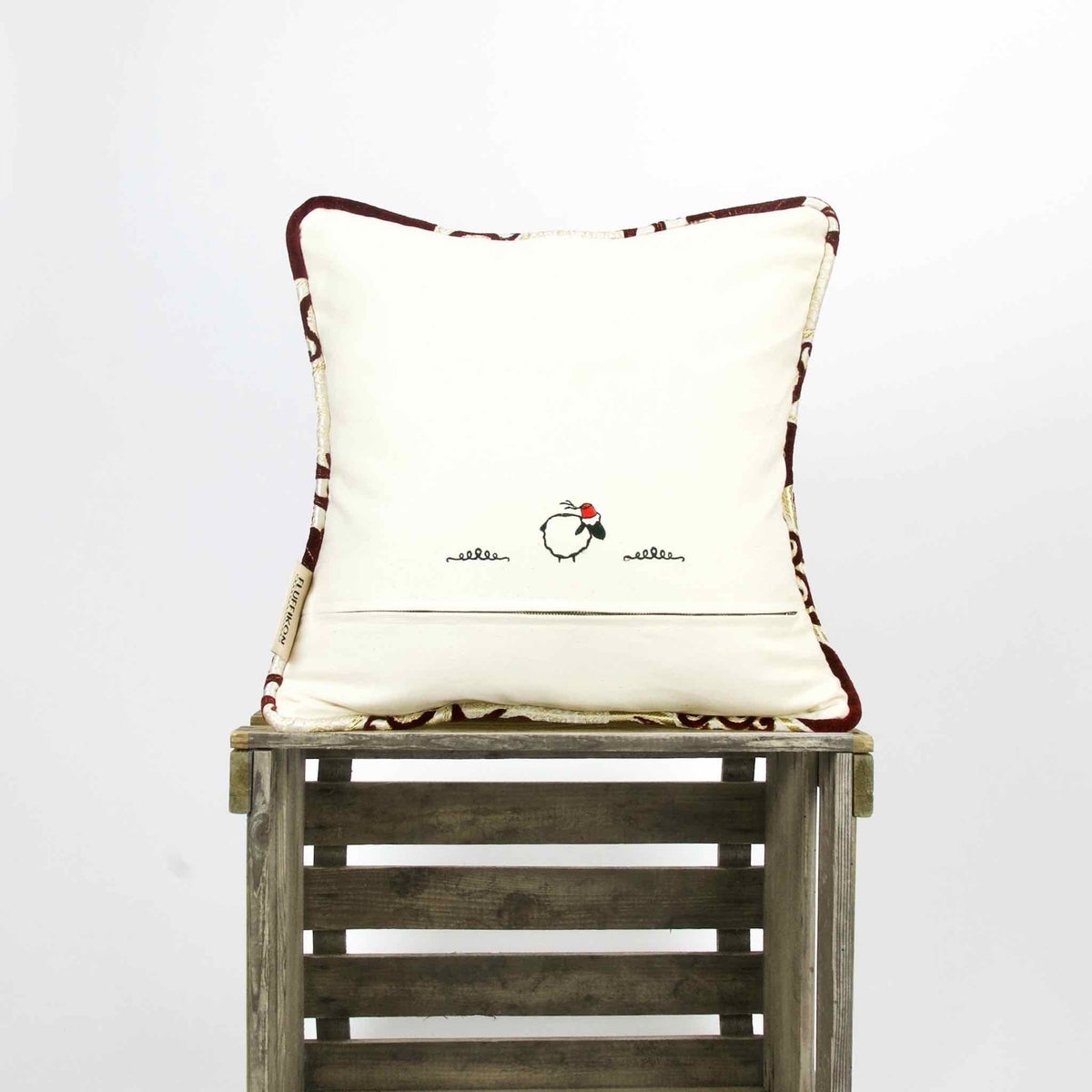 Royal velvet pillow on a wooden box. Stitching on the pillow back is shown.