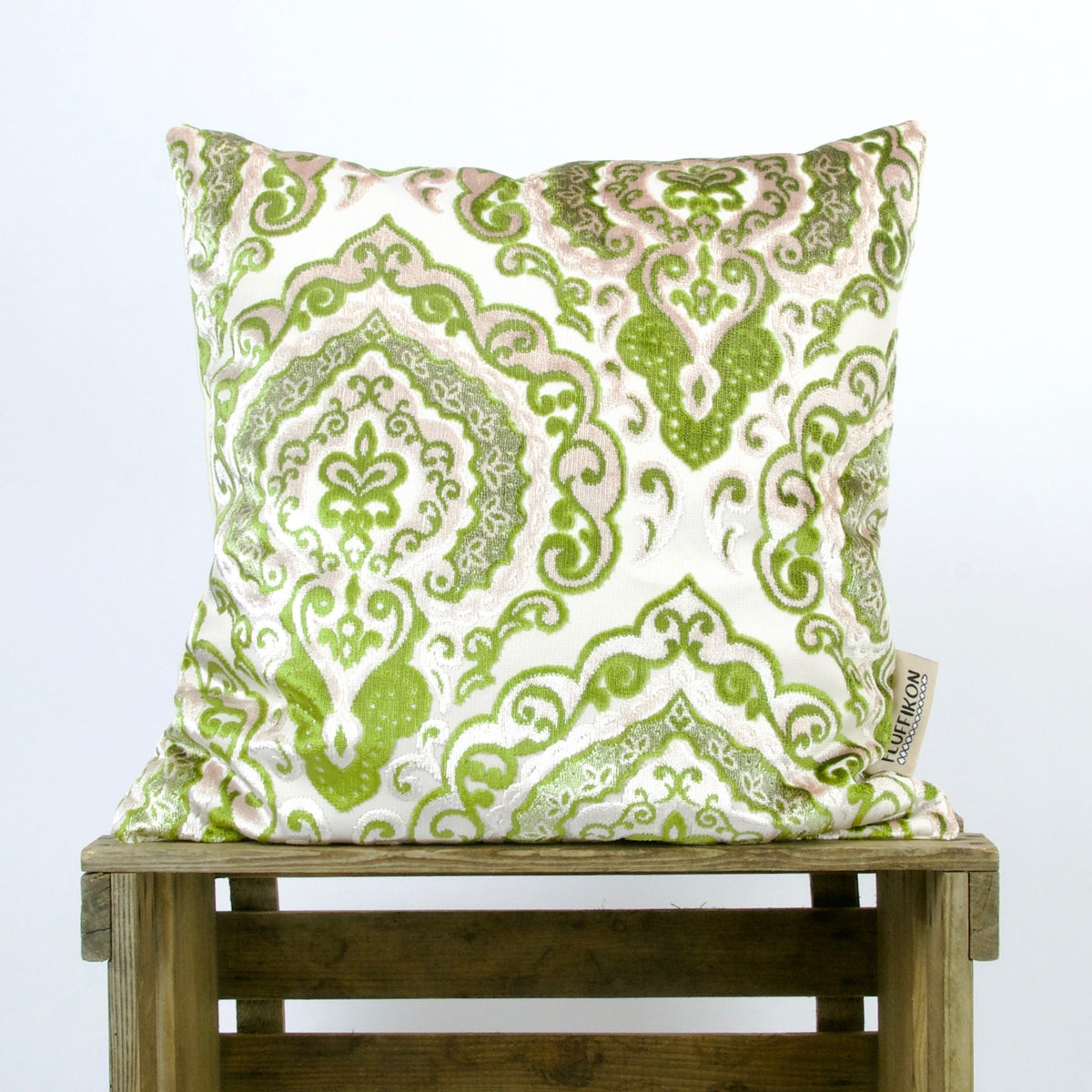 Green velvet throw pillow on a wooden box.