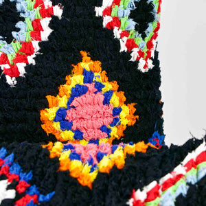 Close view on two black Fluffikon Boucherouite throw pillows. The upcycled pillows have colorful patterns embedded in the black fabric.