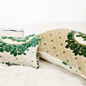 Two large pillows with oriental look on a white bed. The pillows have a traditional green moroccan pattern on a beige canvas background. 