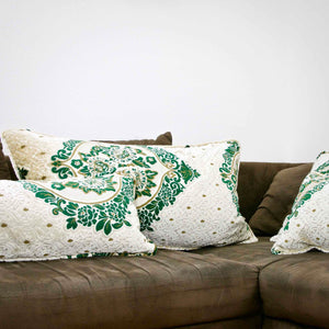 Large pillows with oriental look on a brown sofa. The pillows have a traditional green moroccan pattern on a beige canvas background.