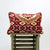 Moroccan velvet cushion with red yellow and white colours on a wooden box.