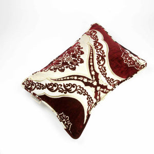 Burgundy velvet decorative pillow which is placed on a white background. The pillow has a typical moroccan look.