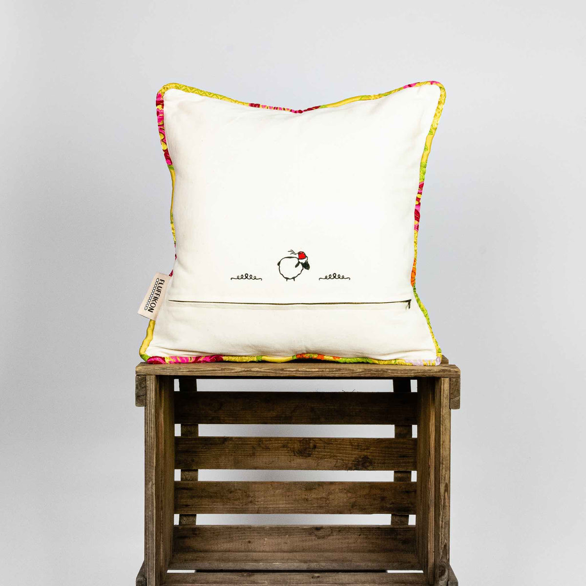 Back of yellow square Brocade pillow on wooden box.