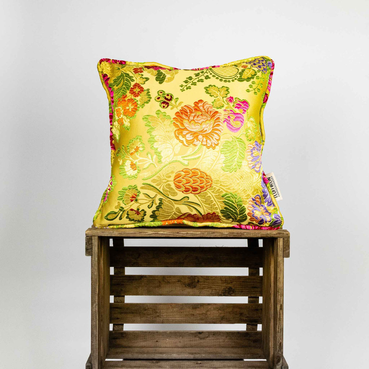 Yellow square Brocade pillow on wooden box.
