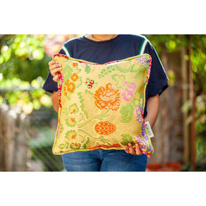 Yellow square Brocade pillow held by a woman.