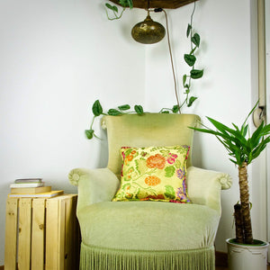 Yellow brocade throw pillow on green velvet chair.