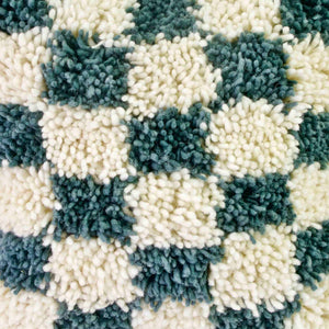 Close up of blue grey checkered Moroccan Fluffikon pillow.