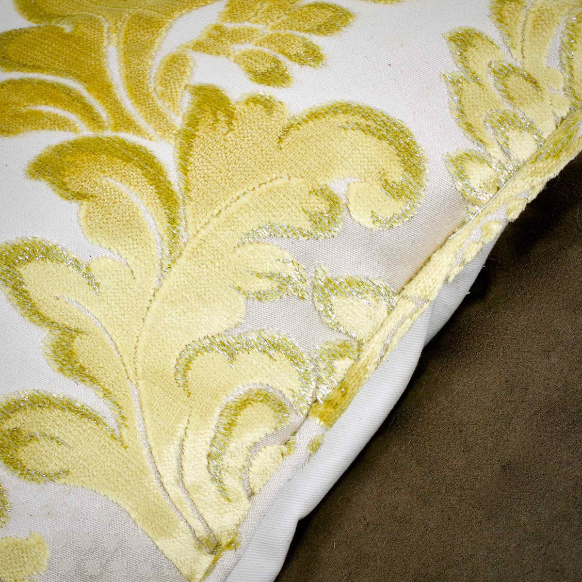 Zoom on the piped edges of a golden Fluffikon oversized couch pillow made from gold velvet fabric.