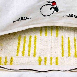 Zoom on the inside of a wool pillow. It is a  handmade Beni Ourain pillow made from a Moroccan rug. The picture also shows the stitched Fluffikon sheep Lalla Soffa on the back of the cushion.